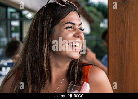 Ritratto vista laterale di una bella bruna sorridente giovane abbronzata. Una donna ragazza felice guarda in lontananza e ride sinceramente. Gioia, piacere da Foto Stock