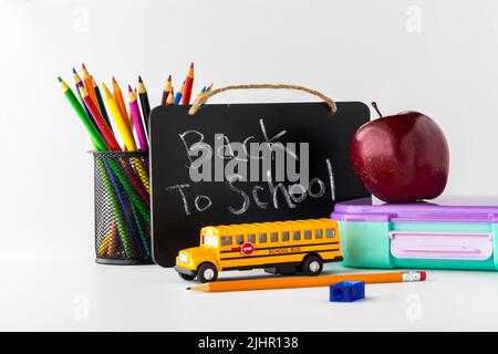 Concetto di ritorno a scuola con oggetti tra cui matite, mela e pranzo. Foto Stock