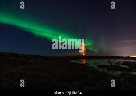 Faro sulla penisola di Reykjanes nortern sotto le luci. L'Islanda. Il timelapse Foto Stock