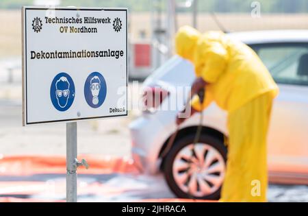 Nordhorn, Germania. 20th luglio 2022. I dipendenti dell'Agenzia federale tedesca per il soccorso tecnico (THW) puliscono e disinfettano un veicolo in un impianto di decontaminazione che viaggiava in un'azienda agricola situata in una zona di sorveglianza. A seguito dell'epidemia di peste suina africana in un'azienda agricola dell'Emsland meridionale, le contee colpite stanno adottando ulteriori misure per combattere la malattia animale. Un centro di logistica comune per le malattie animali ha iniziato le operazioni nelle contee di Grafschaft Bentheim e Emsland a Nordhorn. Credit: Friso Gentsch/dpa/Alamy Live News Foto Stock