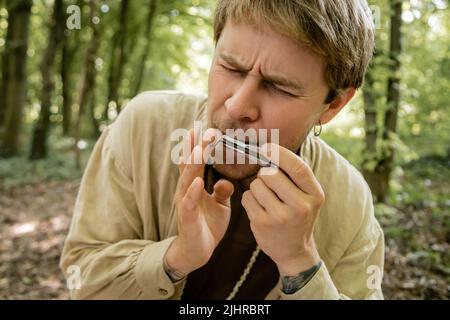 Uomo tatuato che gioca ebrei arpa nella foresta Foto Stock