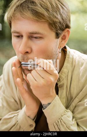 Ritratto dell'uomo che gioca l'arpa degli ebrei nella foresta Foto Stock