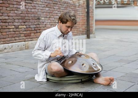 Uomo che gioca a tamburo di hang sulla strada urbana di Venezia Foto Stock