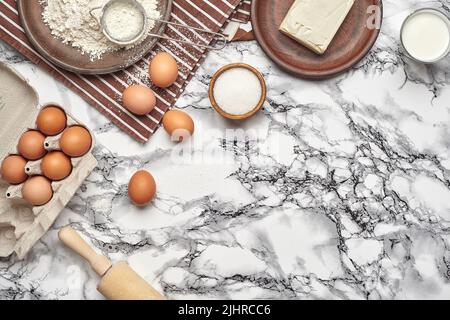 Primo piano. Vista dall'alto di ingredienti da forno e utensili da cucina sullo sfondo del tavolo in marmo. Foto Stock