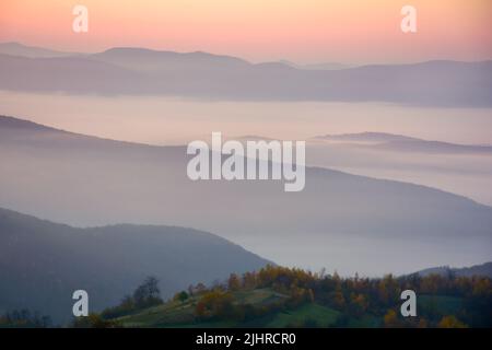 paesaggio di nebbia montagnosa all'alba. paesaggio di nebbia autunnale. splendida vista nella valle distance piena di nebbia mattutina Foto Stock