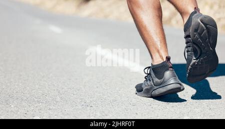 Vista posteriore primo piano di un uomo irriconoscibile che corre all'aperto. Sconosciuto vestito misto corsa maschile jogging su una strada all'aperto durante la sua routine quotidiana di allenamento Foto Stock
