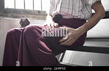Dolore alla coscia in pazienti maschi anziani asiatici. Concetto di sciatica o dolore nervoso sciatico. Foto Stock