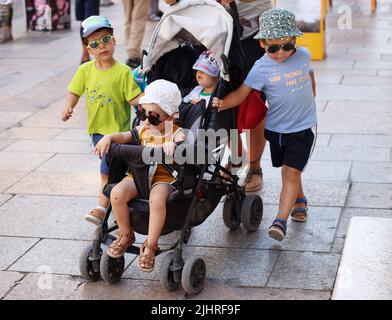 Avignone, Francia. 19th luglio 2022. I bambini che indossano cappelli e occhiali da sole camminano sulla strada in mezzo ad un'onda di calore ad Avignone, Francia, 19 luglio 2022. Credit: Gao Jing/Xinhua/Alamy Live News Foto Stock