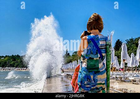 Donna orologi spruzzi d'acqua da forti onde del mare, bulgaro costa del Mar Nero, Bulgaria, Europa, Foto Stock