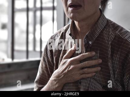 L'anziano asiatico soffre di senso di costrizione toracica. Può essere causato da asma, bronchite, bronchiolite, polmonite, infarto miocardico, h ischemica Foto Stock