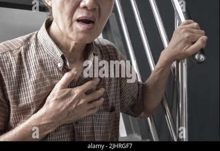 L'anziano asiatico soffre di senso di costrizione toracica. Può essere causato da asma, bronchite, bronchiolite, polmonite, infarto miocardico, h ischemica Foto Stock