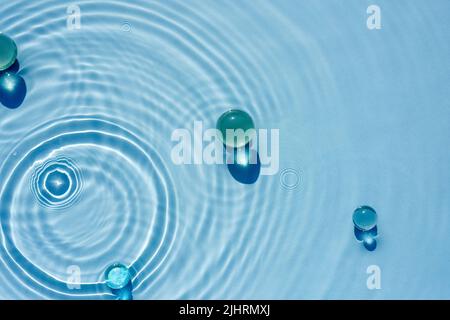 Acqua astratta, fondo cosmetico con onde e increspature e granuli di vetro Foto Stock