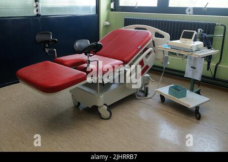 Una sedia-letto ginecologica rossa nella stanza dell'ospedale Foto Stock