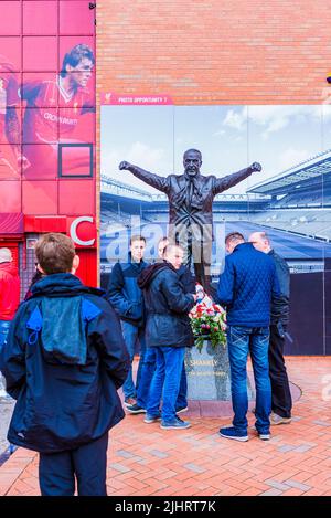 Tifosi di Liverpool F.C. accanto alla statua di Bill Shankly all'Anfield Stadium. Anfield, Liverpool, Merseyside, Lancashire, Inghilterra, Regno Unito Foto Stock