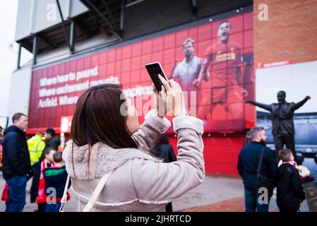 Tifosi di Liverpool F.C. accanto alla statua di Bill Shankly all'Anfield Stadium. Anfield, Liverpool, Merseyside, Lancashire, Inghilterra, Regno Unito Foto Stock