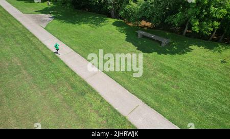 Uno scatto aereo di un parco con un uomo che corre su una strada a piedi Foto Stock