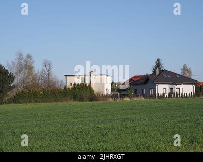 Terreno verde e case nella città europea di Bielsko-Biala nel distretto della Slesia in Polonia, cielo azzurro chiaro in 2020 caldo sole giorno di primavera il mese di aprile. Foto Stock