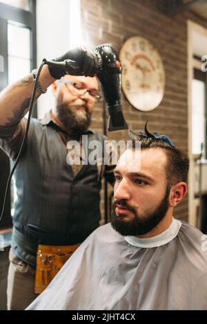 Elegante barbiere asciugando i capelli mans in barbiere Foto Stock