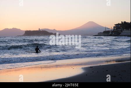 Il tramonto colora la spiaggia di Kamakura. Monte Fuji e l'isola di Enoshima sono sullo sfondo. Foto Stock