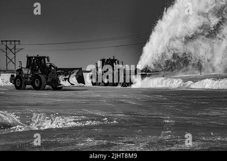Una scala di grigi di trattori che sgombrano la neve Foto Stock