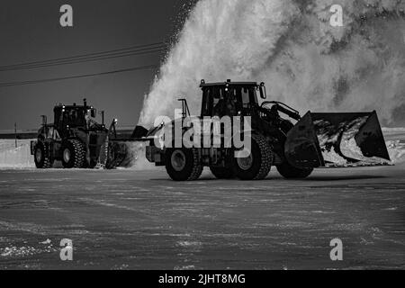 Una scala di grigi di trattori che sgombrano la neve Foto Stock