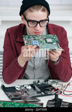 Programmatore che studia CPU guasta in officina Foto Stock