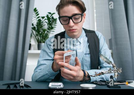 Giovane uomo che guarda seriamente lo schermo dello smartphone Foto Stock