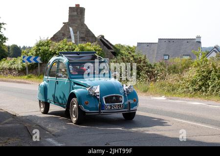 Kerlaz, Francia - Luglio 17 2022: Coppia in pensione in crociera in un verde Citroën 2CV con due bandiere bretone nella parte anteriore. Foto Stock