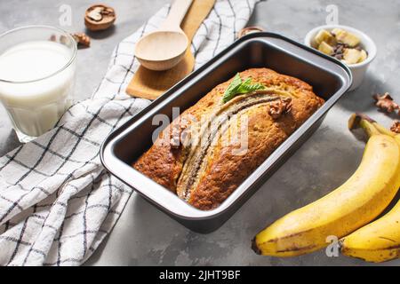 Pane banana o torta in metallo forma di cottura su tavola di cemento. Delizioso dessert fatto in casa, gustoso snack o colazione al mattino. Foto Stock