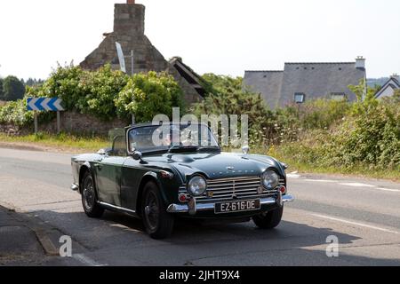 Kerlaz, Francia - Luglio 17 2022: Coppia in pensione in crociera in un verde Triumph TR5 sport convertibile. Foto Stock