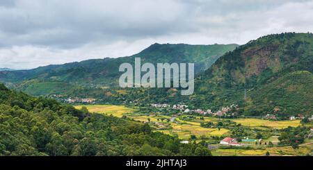 Tipico paesaggio del Madagascar a Mandraka regione. Colline coperte di verde fogliame, piccoli villaggi in distanza, su nuvoloso giorno Foto Stock