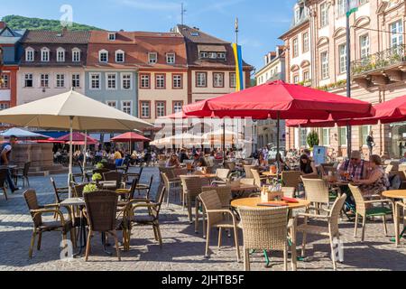 Heidelberg, Germania: Giugno 2. 2022: Caffè all'aperto con ombrelloni e posti a sedere nella storica piazza del mercato di Heidelberg, nella Germania meridionale Foto Stock