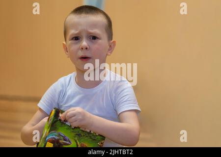 Il ragazzino grida di dolore e di risentimento. Si strappa le lacrime dalla guancia con la mano. Foto di alta qualità Foto Stock