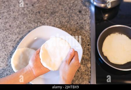 Donna mani che fanno arepas in cucina. Cibo latino. Foto Stock