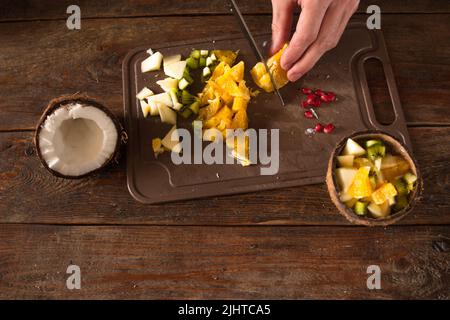 Preparazione dell'insalata di frutta in guscio di cocco Foto Stock