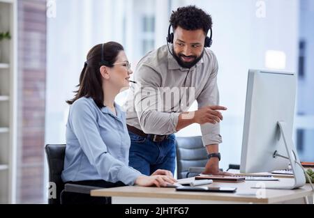 Agente di telemarketing misto del call center di gara che addestra il nuovo assistente caucasico su un computer in un ufficio. Soluzione per la risoluzione dei problemi di Supervisor Manager Foto Stock