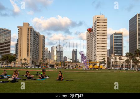 Tel-Aviv, Israele - 19 Luglio, 2022, la gente riposa nel parco vicino alla spiaggia al tramonto, legge libri, guarda il tramonto, parla, fai yoga. La gente vola aquiloni. Foto Stock