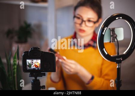 Donna di bellezza blogger fa video revisione di cosmetici a casa Foto Stock