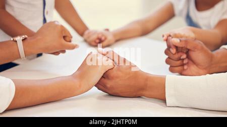 Primo piano della coppia che tiene le mani e prega con i loro bambini al tavolo. Genitori e figli che dicono preghiera e adorano insieme. Avere speranza e fede Foto Stock