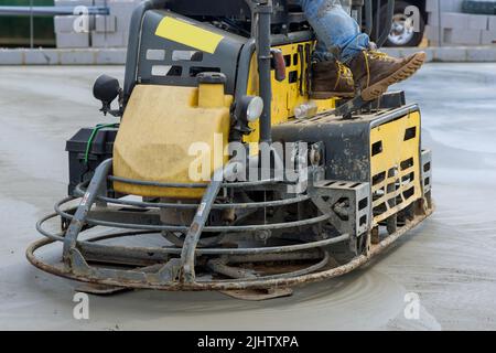 I lavoratori utilizzano macchine per la lucidatura del cemento dopo aver versato il calcestruzzo sul pavimento della fondazione Foto Stock