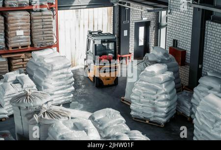 Carrello elevatore in magazzino con sacchi di grano per l'esportazione. Concetto di distribuzione e logistica. Foto Stock