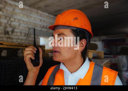 Il lavoratore di costruzione nel casco parla alla radio Foto Stock