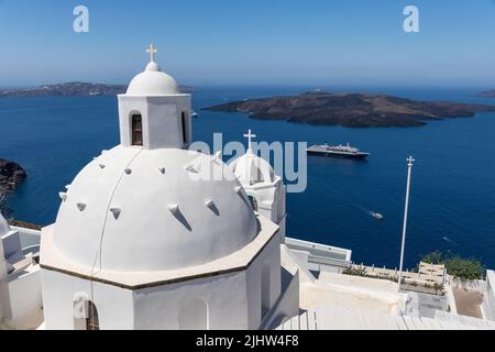 Chiesa di Agios Minas a Fira / Thira. Una chiesa greca ortodossa con una cupola bianca e il campanile. Vista sul Mar Egeo e Vulcano, Santorini, Grecia Foto Stock