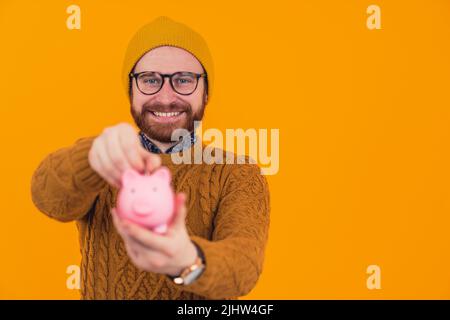 Il giovane uomo è il suo 20s con una moneta e una banca piggy - risparmio e futuro per i giovani concetto. Foto di alta qualità Foto Stock