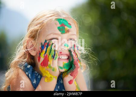 La felicità può essere trovata in una vasca di vernice. Una ragazza piccola felice coperta di vernice. Foto Stock