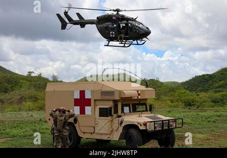 Un elicottero dell'esercito degli Stati Uniti UH-72 Lakota assegnato all'aviazione dell'esercito, comando di truppa 101st della guardia nazionale dell'esercito di Porto Rico, vola sopra un'ambulanza di Humvee dal supporto 1065th dell'area della compagnia medica della guardia nazionale dell'esercito di Porto Rico durante la formazione annuale al centro di addestramento congiunto di Camp Santiago, Salinas, Puerto Rico, 15 luglio 2022. I medici sono stati testati su vari compiti, tra cui fornire un trattamento immediato delle vittime per elemento, con sezione trauma, laboratorio, e servizi a raggi X per una diagnostica rapida e accurata come parte dei loro requisiti di formazione come farmaci di combattimento per il futuro d Foto Stock