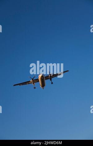 Vista dal basso di un velivolo turboprop sull'approccio finale per l'atterraggio. Foto Stock