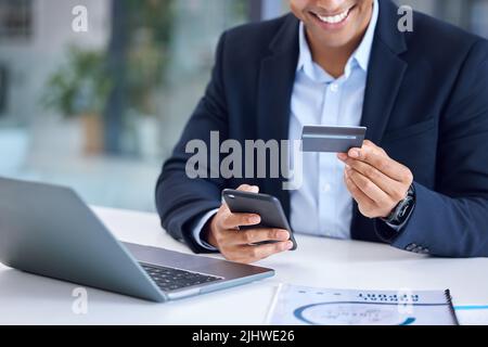 Ora che il commercio sta facendo bene, posso comprare alcuni aggiornamenti. Primo piano di un uomo d'affari irriconoscibile utilizzando un cellulare e carta di credito in un Foto Stock