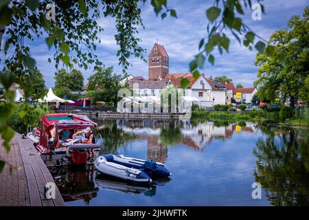 Parchim, Germania. 18th luglio 2022. Un motoscafo è ormeggiato nel porto di Elde di fronte alla chiesa di Santa Mariena. Per i turisti in barca e i viaggiatori individuali, l'ex sede della contea è un consiglio da parte di chi viaggia per una serie di giorni di vacanza. Credit: Jens Büttner/dpa/Alamy Live News Foto Stock