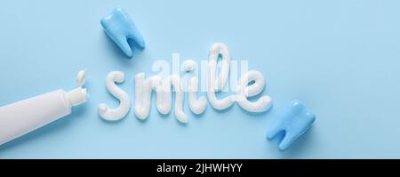 Parola SORRISO scritto con dentifricio su sfondo azzurro chiaro Foto Stock